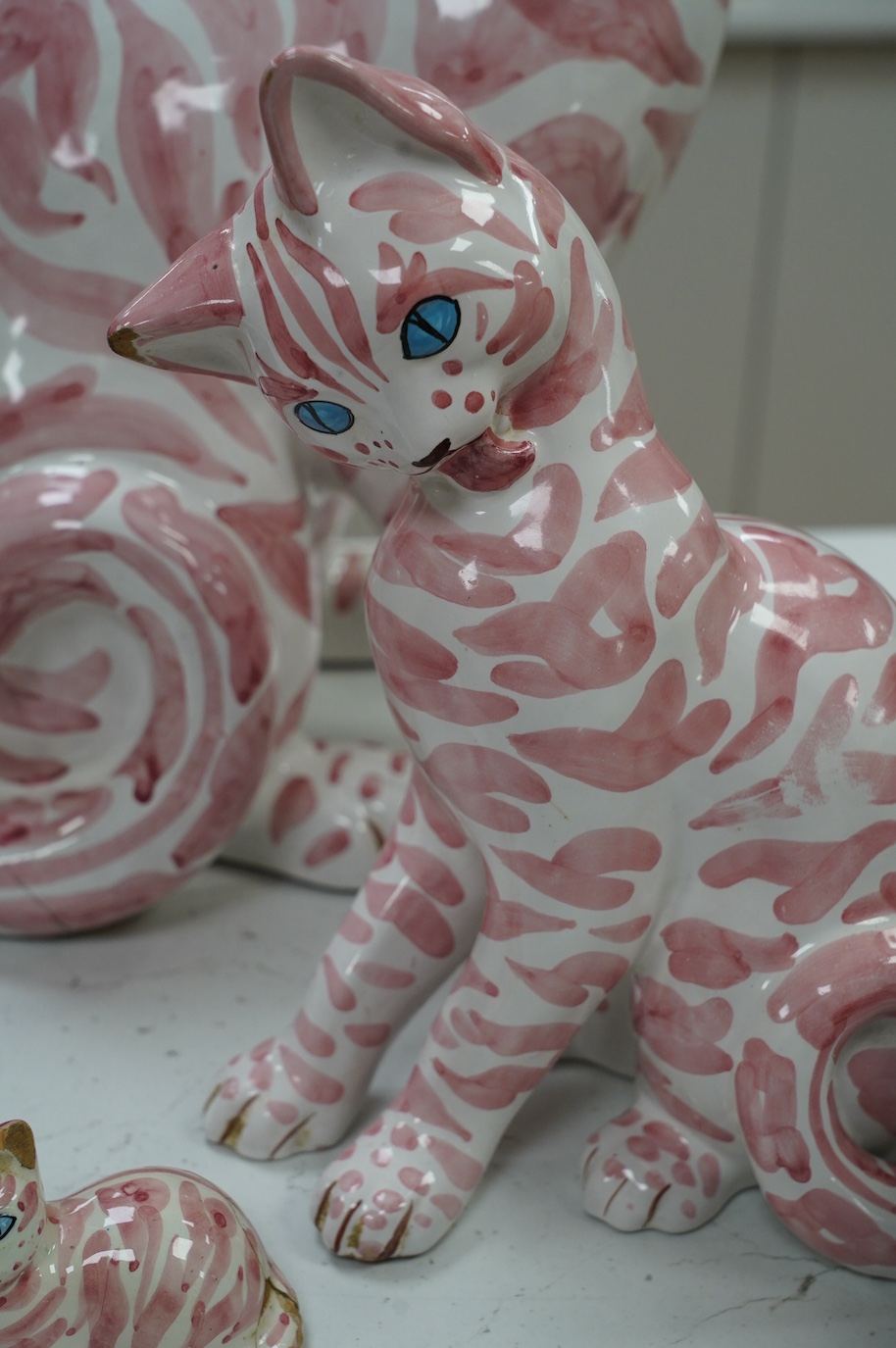 A large 1950's Italian pink maiolica seated cat and two smaller, largest 45cm. Condition - poor